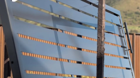 Metal livestock trailer with horizontal orange reflectors and metal railings against hillside background