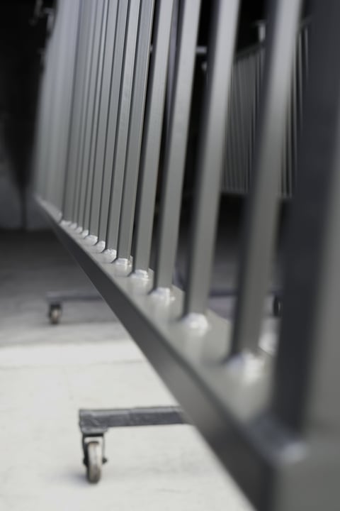 Close-up of a portable space heater with vertical heating elements and wheels on a light floor