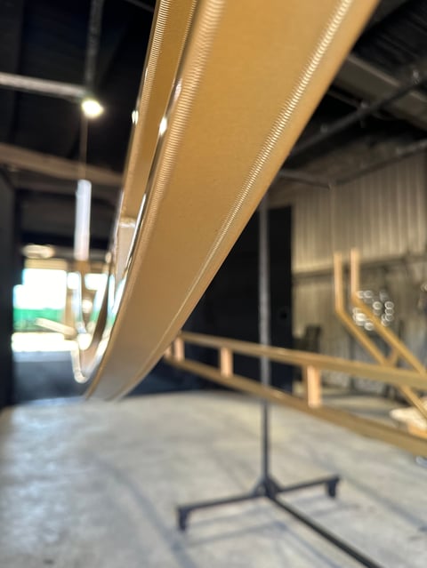 Close-up of a tan and white aircraft fuselage at night in a hangar with support structures visible